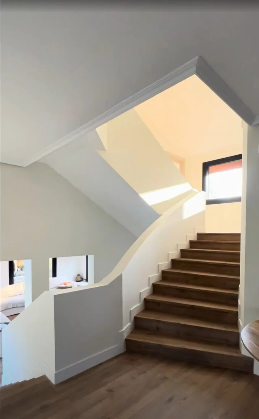 Escalera renovada con peldaños de madera y luz natural · Ana Uría Interiorismo