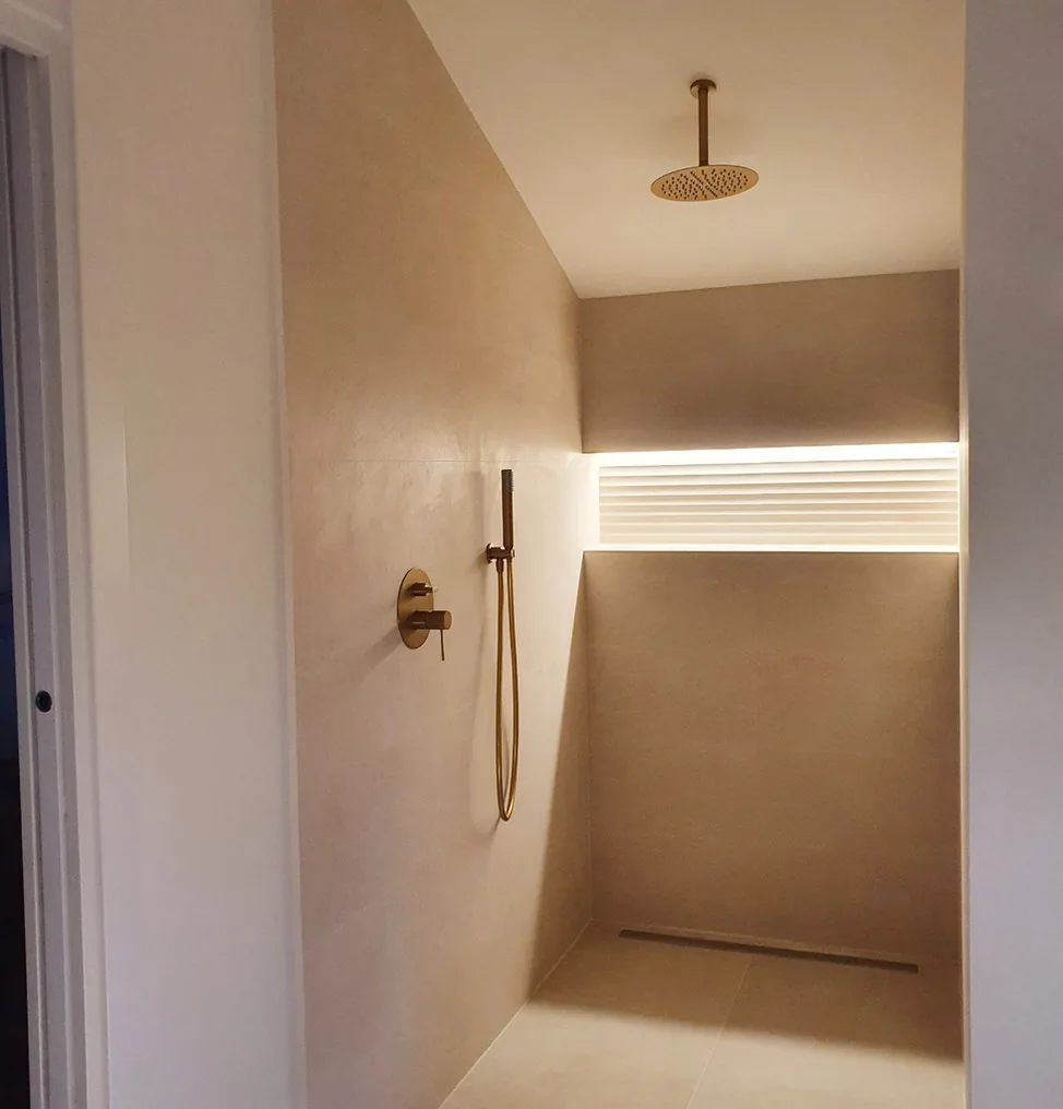 Ducha de obra con grifería dorada e iluminación LED · Ana Uría Interiorismo