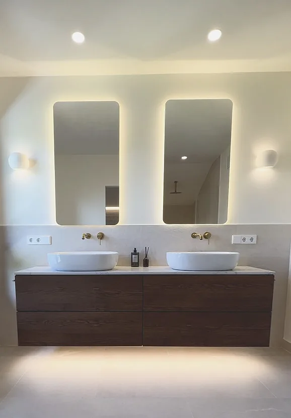 Baño con doble lavabo, espejos retroiluminados y mueble de madera · Ana Uría Interiorismo