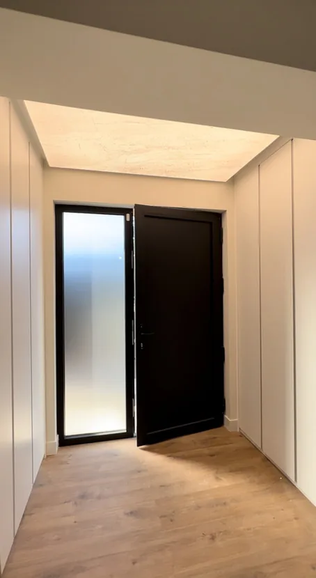 Recibidor con puerta de entrada negra y armario empotrado blanco · Ana Uría Interiorismo